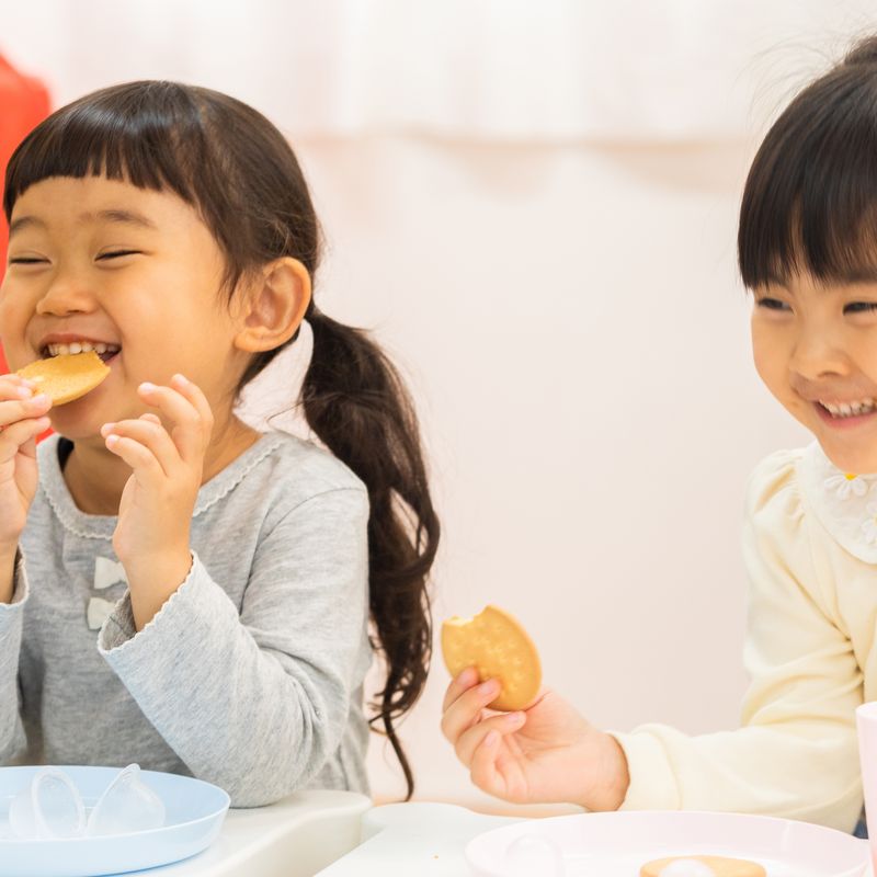 おやつを食べて笑い合うこどもたち(イメージ)