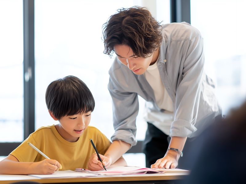 お兄さん先生と勉強するこども(イメージ)